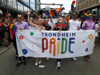 Pride parade. Foran bæres en stor vimpel med teksten "Trondheim Pride"